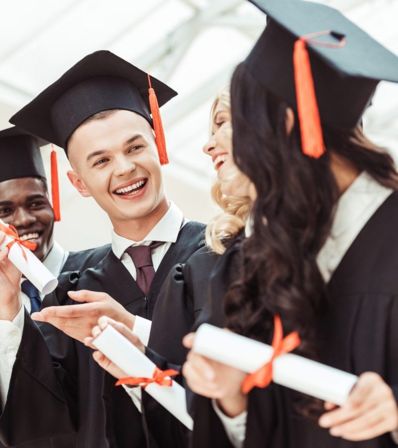 laughing graduated multiethnic students with diplomas